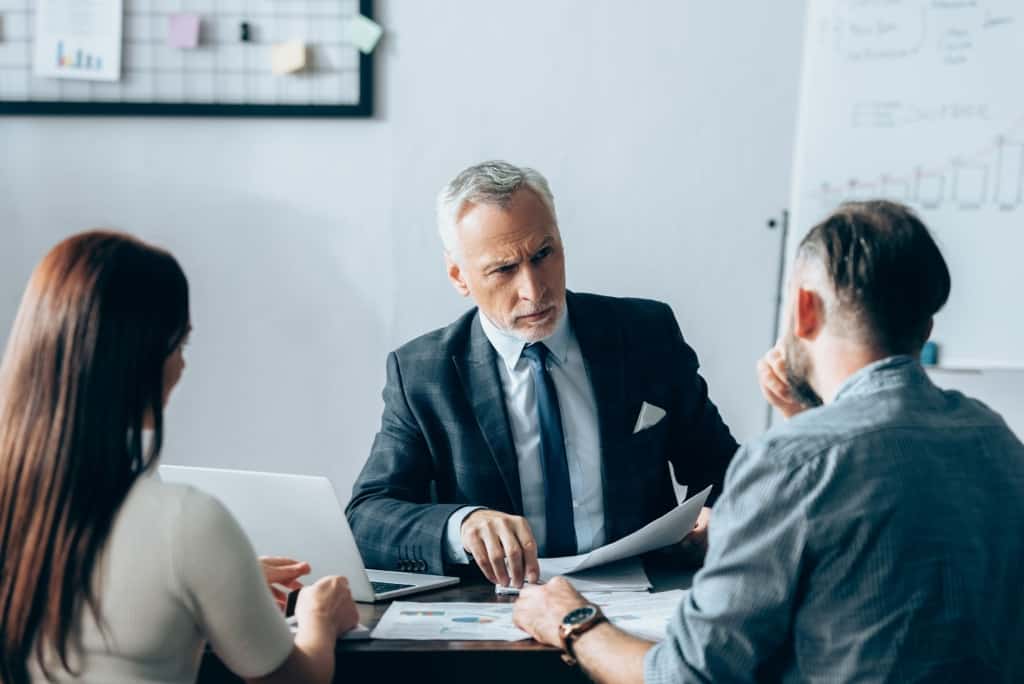 Mature security consultant discussing security plans with young high net worth couple